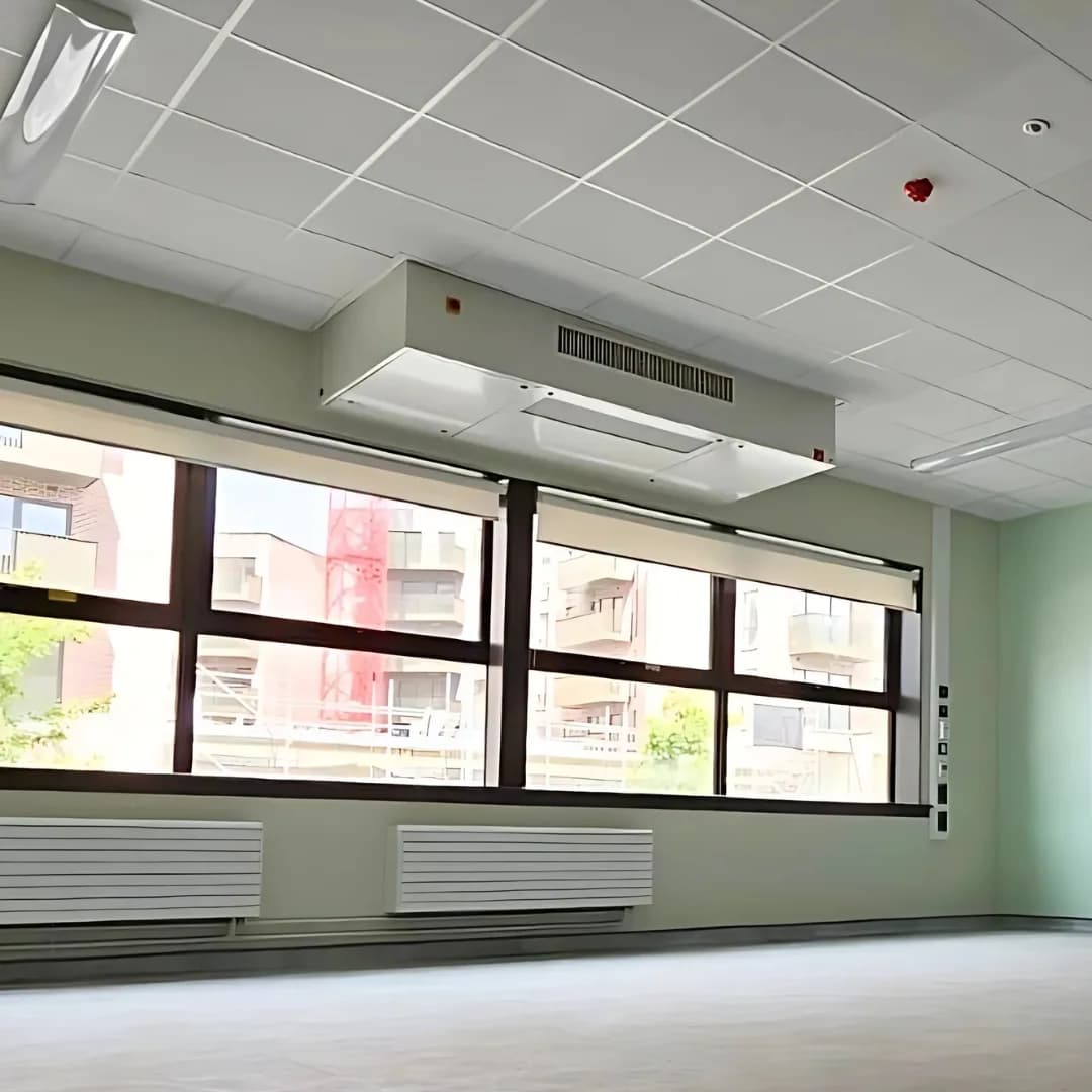 Eversky onder het plafond van een leeg lokaal, boven een rij ramen met radiatoren eronder